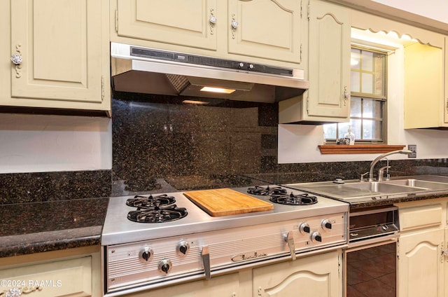 kitchen with decorative backsplash, cream cabinetry, gas stovetop, tile patterned flooring, and sink