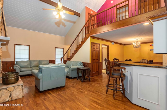 living room featuring ceiling fan with notable chandelier, dark hardwood / wood-style floors, ornamental molding, and high vaulted ceiling