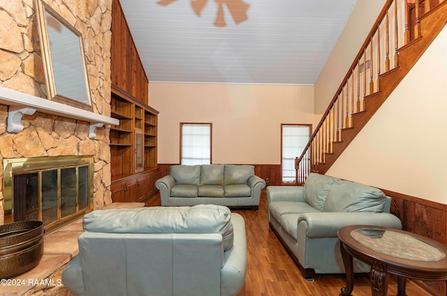 living room featuring hardwood / wood-style flooring, a fireplace, wooden walls, and high vaulted ceiling