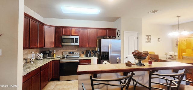 kitchen with appliances with stainless steel finishes, hanging light fixtures, decorative backsplash, and a breakfast bar