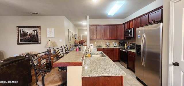 kitchen with tasteful backsplash, a breakfast bar area, an island with sink, sink, and stainless steel appliances