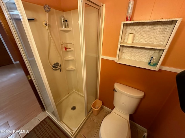 bathroom with toilet, tile patterned floors, and a shower with shower door