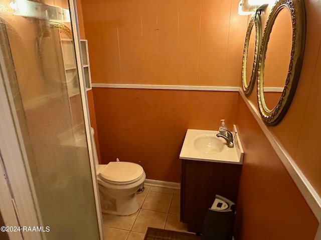 bathroom with tile patterned flooring, a shower with door, vanity, and toilet