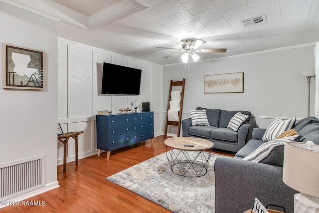 living room with light wood-type flooring, ornamental molding, and ceiling fan