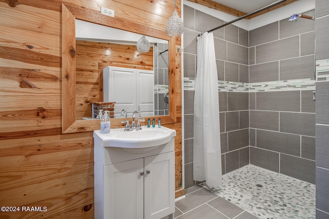 bathroom with tile patterned flooring, wood walls, a shower with shower curtain, and vanity