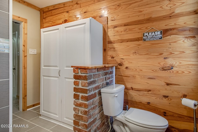 bathroom with wood walls, toilet, and tile patterned floors