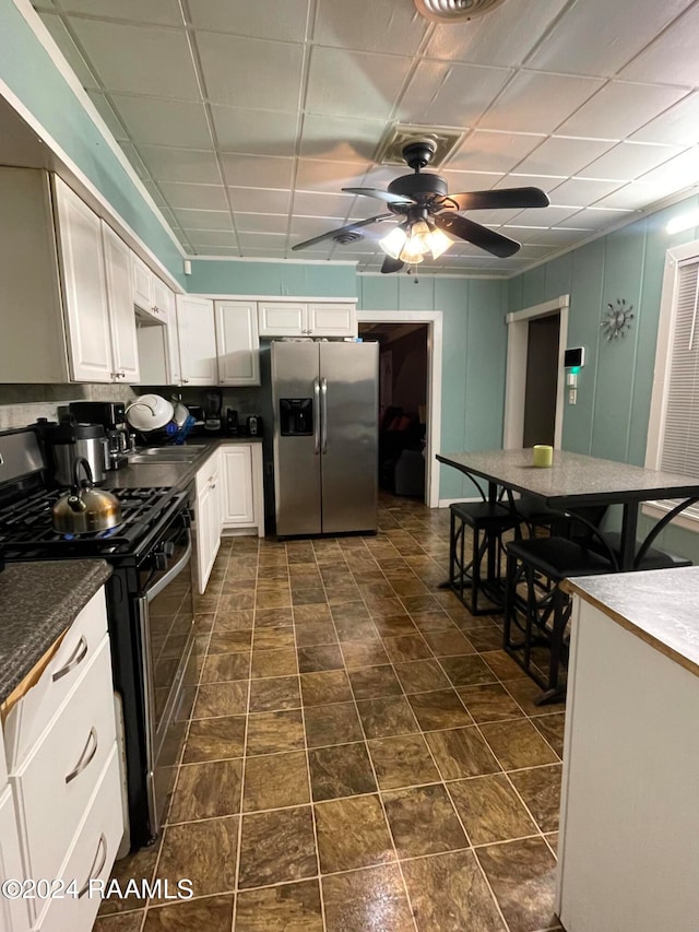 kitchen featuring appliances with stainless steel finishes, a drop ceiling, white cabinetry, and ceiling fan