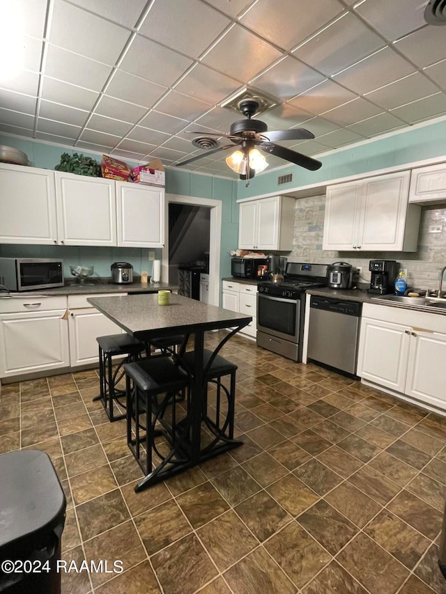 kitchen with ceiling fan, white cabinets, sink, appliances with stainless steel finishes, and decorative backsplash