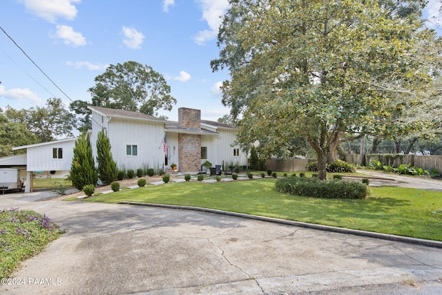 view of front facade with a chimney, a front lawn, and fence