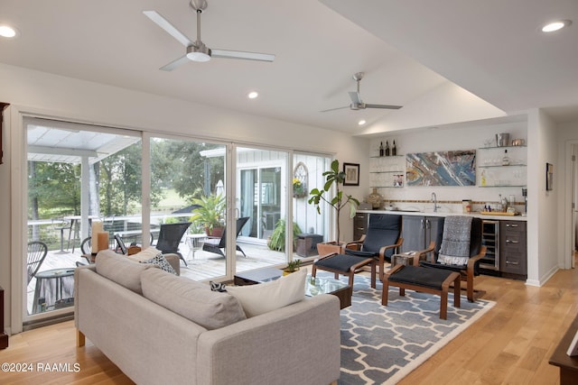 living room with ceiling fan, wine cooler, light wood-type flooring, and bar