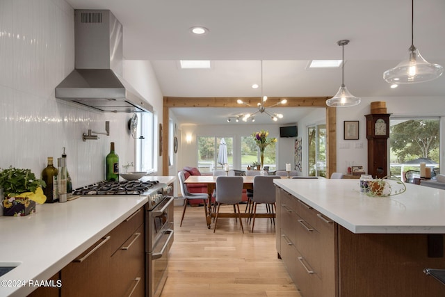kitchen featuring light countertops, modern cabinets, wall chimney exhaust hood, double oven range, and open floor plan