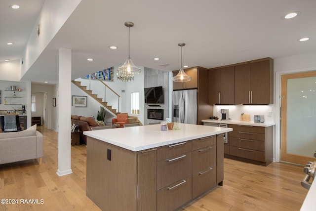 kitchen with stainless steel refrigerator with ice dispenser, decorative light fixtures, light hardwood / wood-style floors, and a kitchen island