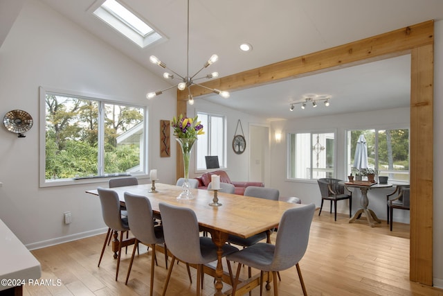 dining space with light wood-type flooring, baseboards, and vaulted ceiling with skylight