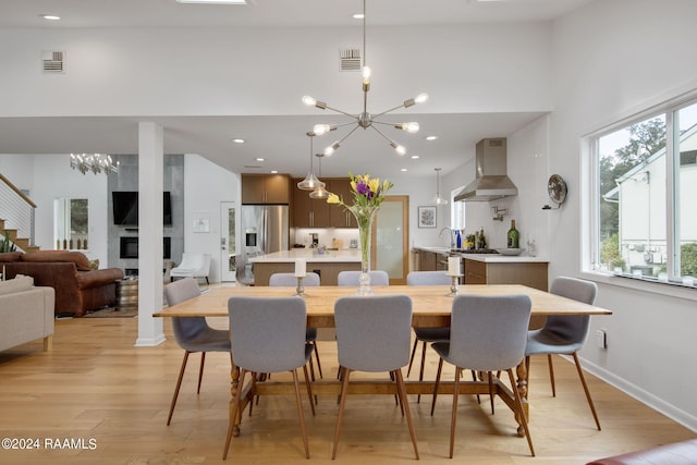 dining room with an inviting chandelier, light wood-type flooring, a towering ceiling, and sink