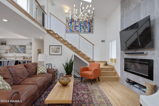 living room featuring stairway, a high ceiling, wood finished floors, visible vents, and a notable chandelier