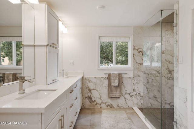 bathroom with a marble finish shower, a sink, and double vanity