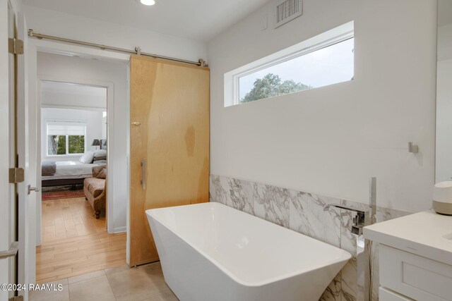 full bath featuring connected bathroom, vanity, a freestanding bath, visible vents, and recessed lighting