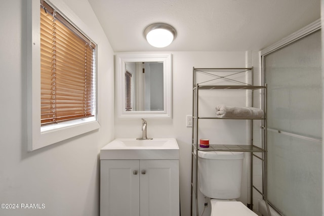 bathroom featuring a textured ceiling, a shower with shower door, vanity, and toilet