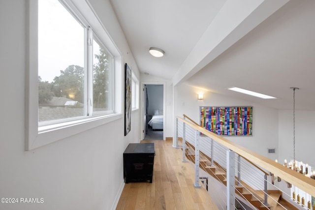 corridor with hardwood / wood-style flooring, a chandelier, and vaulted ceiling