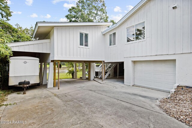 view of front of property featuring a carport, concrete driveway, an attached garage, stairs, and board and batten siding