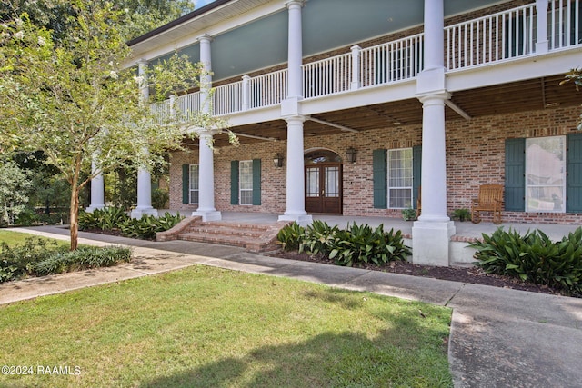 view of front facade with a balcony, covered porch, and a front yard