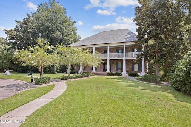 view of front of home with a balcony and a front yard