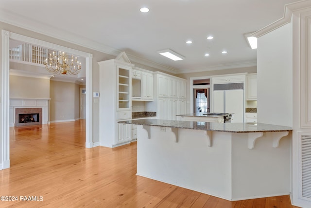 kitchen featuring light wood-type flooring, white cabinetry, kitchen peninsula, and a breakfast bar area