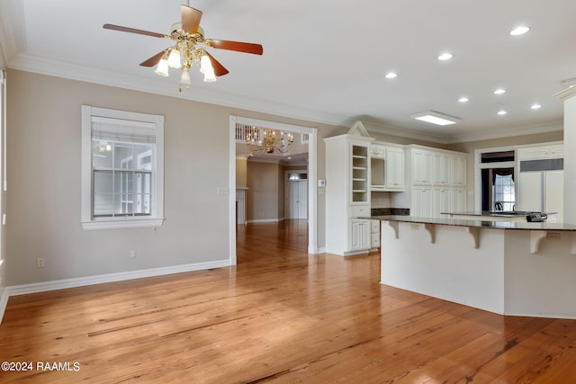 kitchen featuring white cabinets, a breakfast bar, kitchen peninsula, light wood-type flooring, and crown molding