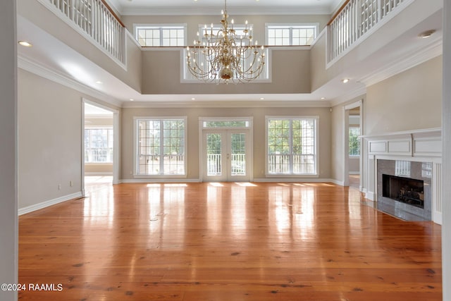 unfurnished living room with a high ceiling, light wood-type flooring, and crown molding