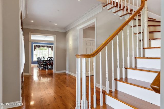 stairs with wood-type flooring and crown molding