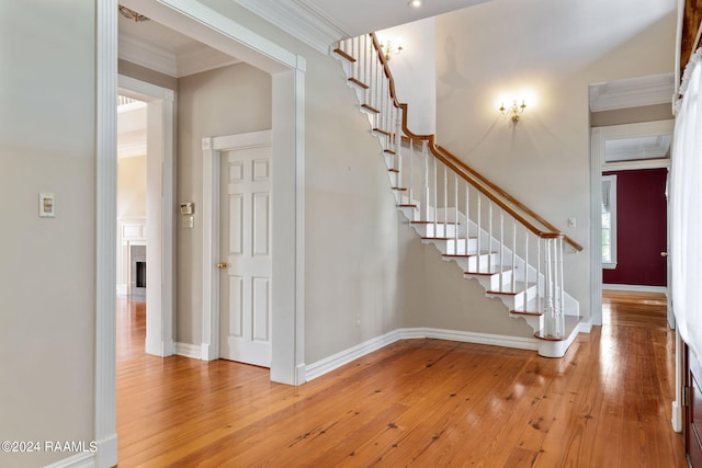 stairway with ornamental molding and wood-type flooring