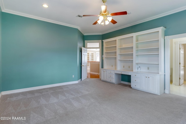 unfurnished bedroom featuring built in desk, ornamental molding, ceiling fan, and light colored carpet