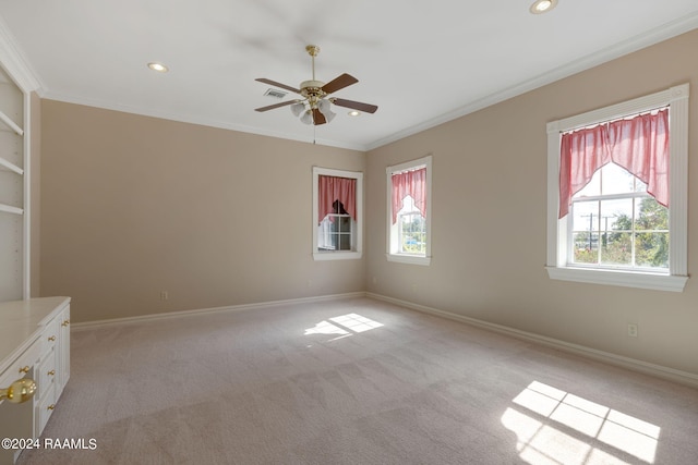 spare room with light carpet, a healthy amount of sunlight, and crown molding