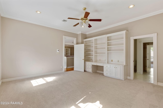 unfurnished bedroom with built in desk, ornamental molding, ceiling fan, and light carpet