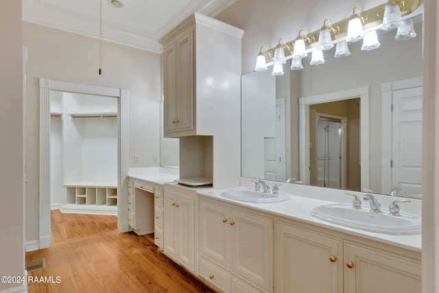 bathroom with wood-type flooring, vanity, ornamental molding, and a shower with shower door