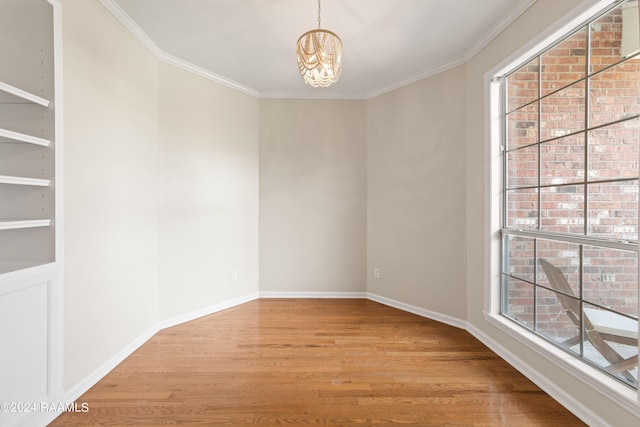 empty room with light wood-type flooring, a chandelier, and a healthy amount of sunlight