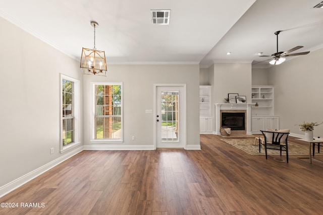 living room featuring ceiling fan with notable chandelier, ornamental molding, dark wood-type flooring, and a premium fireplace