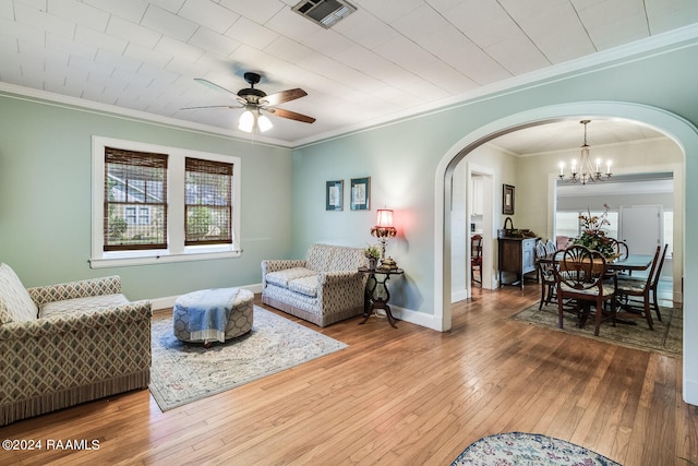 living room with ceiling fan with notable chandelier, ornamental molding, and hardwood / wood-style floors