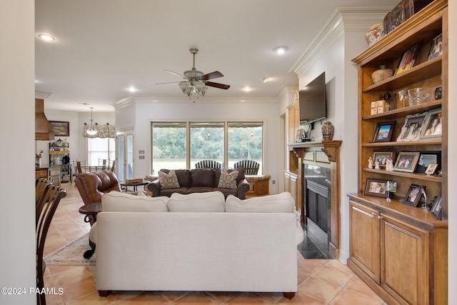 tiled living room featuring ceiling fan with notable chandelier, crown molding, and a premium fireplace