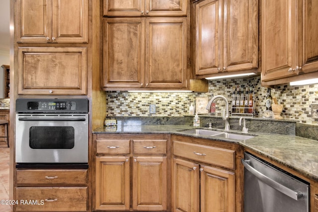 kitchen with dark stone countertops, stainless steel appliances, sink, and tasteful backsplash