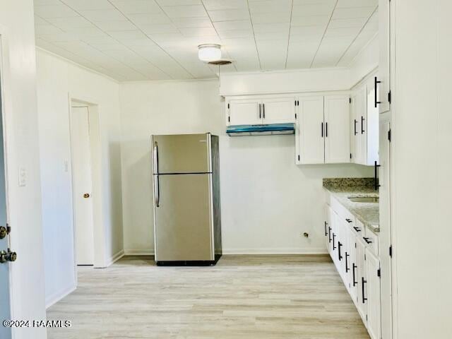 kitchen featuring light wood-type flooring, stainless steel fridge, white cabinetry, and light stone countertops