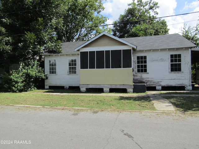 view of front of house with a sunroom and a front yard