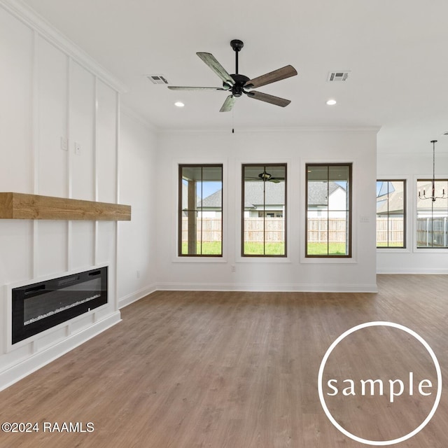 unfurnished living room with hardwood / wood-style floors, ceiling fan with notable chandelier, and ornamental molding