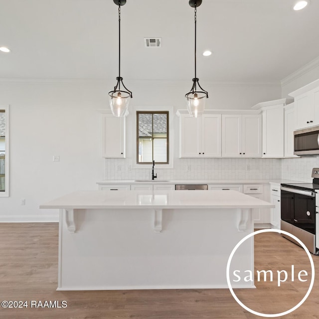 kitchen featuring white cabinetry, sink, tasteful backsplash, a kitchen island, and appliances with stainless steel finishes