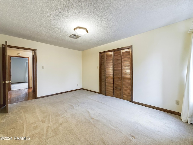 unfurnished bedroom with a textured ceiling, light colored carpet, and a closet