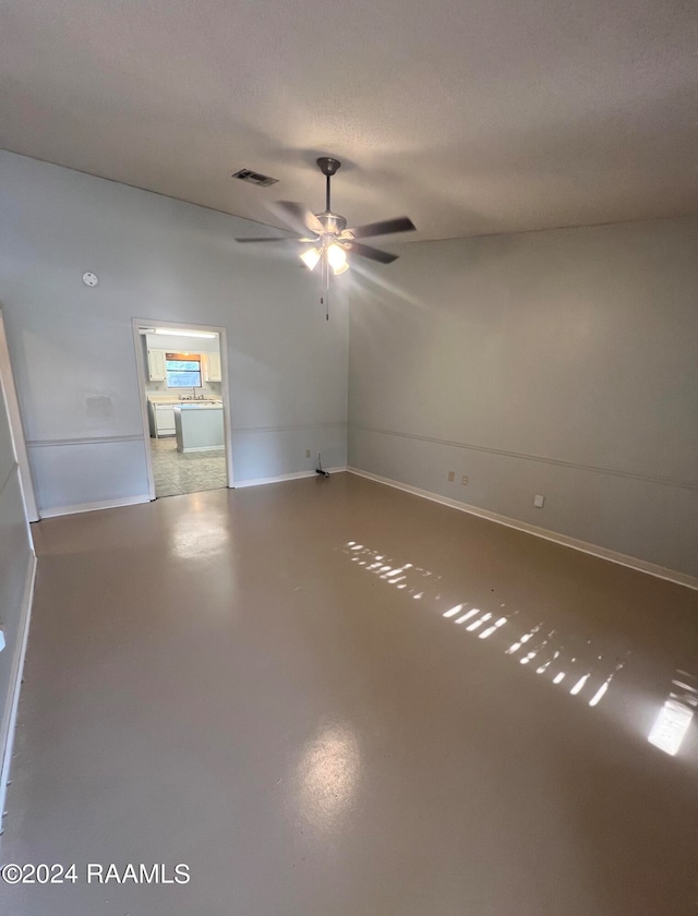 unfurnished room with a textured ceiling, ceiling fan, and concrete flooring