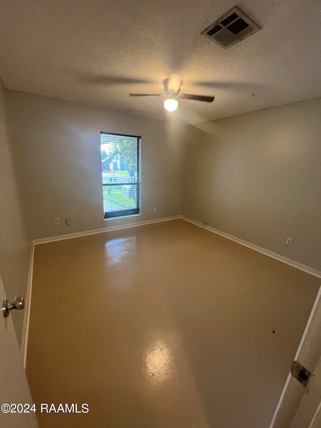 spare room with ceiling fan, a textured ceiling, and concrete flooring