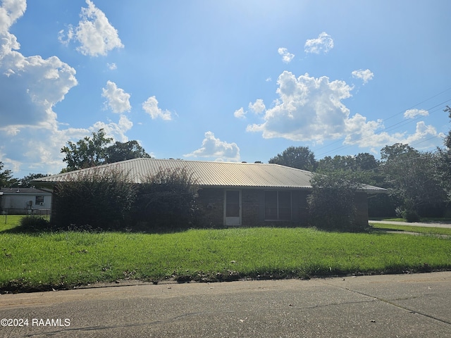 view of side of home featuring metal roof and a lawn