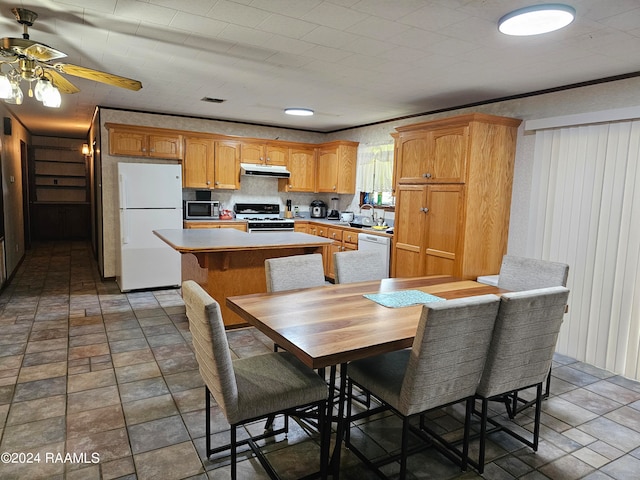 kitchen featuring white appliances, a kitchen breakfast bar, sink, ceiling fan, and a kitchen island