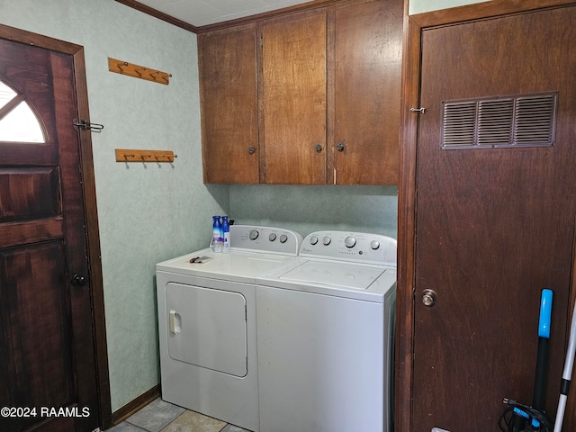 washroom featuring washing machine and dryer, light tile patterned floors, and cabinets